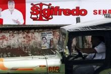 Un conductor pasa con su vehículo junto a una valla de publicidad política en la ciudad de Buenaventura, principal puerto marítimo del Pacífico, ubicado al occidente del departamento del Valle del Cauca (Colombia), este 8 de marzo de 2014, en la víspera de las elecciones legislatias en el país. EFE