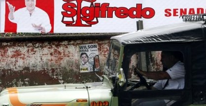Un conductor pasa con su vehículo junto a una valla de publicidad política en la ciudad de Buenaventura, principal puerto marítimo del Pacífico, ubicado al occidente del departamento del Valle del Cauca (Colombia), este 8 de marzo de 2014, en la víspera de las elecciones legislatias en el país. EFE