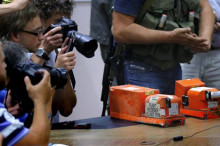 Periodistas toman imágenes de las dos cajas negras del vuelo MH17 de Malaysian Airlines antes de ser entregadas por separatistas prorrusos al coronel Mohamed Sakri (fuera de cuadro), del Consejo Nacional de Seguridad de Malasia. EFE
