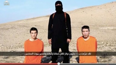 Captura de un video publicado en YouTube por Al- Furqan Medios el 20 de enero de 2015 que muestra a un miliciano del Estado Islámico de pie entre dos rehenes japoneses identificados como Haruna Yukawa (d) y Kenji Goto (i) . EFE/EPA